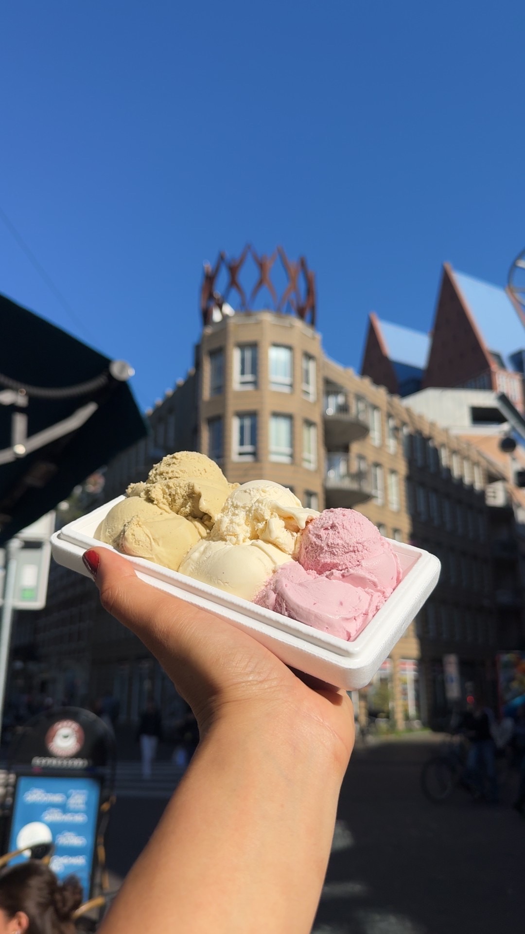 Een bakje met meerdere smaken ijs, buiten in de stad
